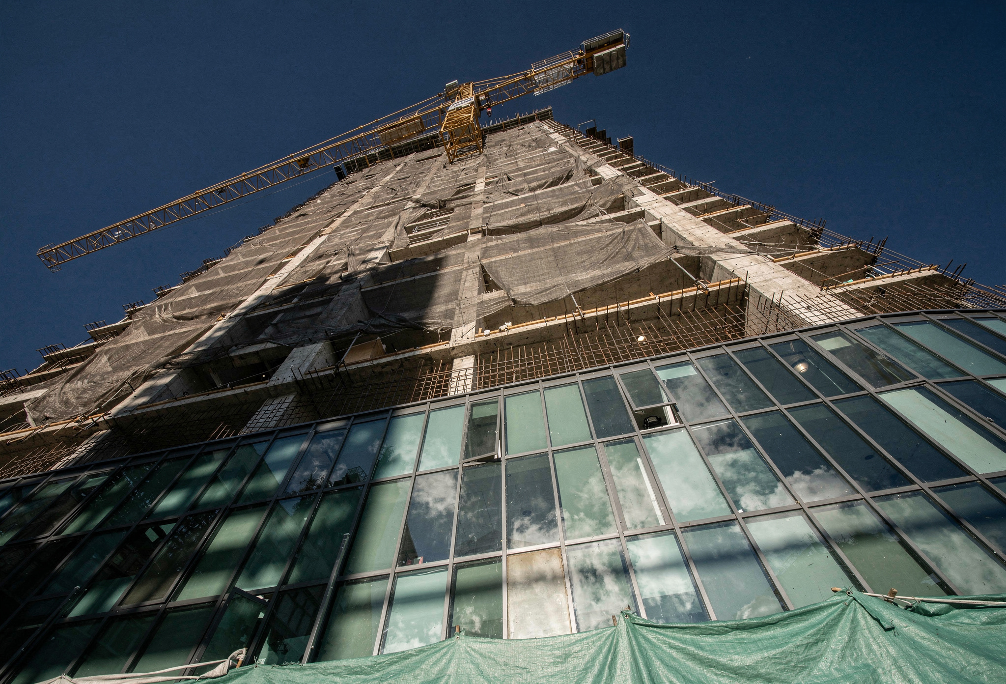 Pre-construction condo tower with a yellow crane against a deep blue sky